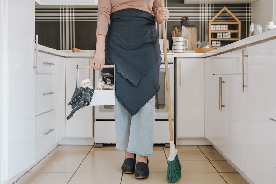 A person standing in a kitchen holding a broom